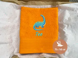 Leuchtend oranges Handtuch mit blauem Dinosaurier-Stickmotiv von HeldenFaden. Perfekt für personalisierte Bestickung und als Geschenk geeignet.