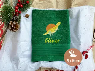 Grünes Handtuch mit gelbem Dinosaurier-Stickmotiv von HeldenFaden. Perfekt für personalisierte Gestaltung.