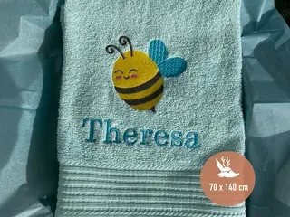 Mintfarbenes Handtuch mit gelbem Bienen-Stickmotiv und personalisierter Bestickung in Blau von HeldenFaden. Ideal für Kinder und als Geschenk geeignet.