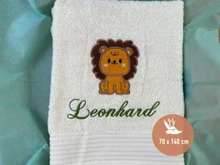 Beigefarbenes Handtuch mit Löwen-Stickmotiv und grünem personalisierten Schriftzug von HeldenFaden. Ideal für Kinder und personalisierte Geschenkideen.
