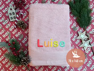 Rosafarbenes Handtuch mit personalisierter Bestickung in Regenbogenfarben von HeldenFaden. Ideal als farbenfrohes und individuelles Geschenk.