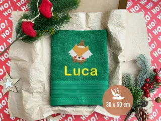 Grünes Handtuch (30x50 cm) mit einem gestickten Weihnachtsfuchs-Motiv und gelbem Schriftzug 'Luca'. Personalisierbar und festlich.