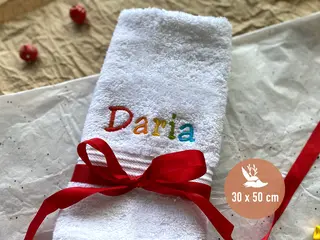Weißes Handtuch (30x50 cm) mit personalisierter Regenbogen-Bestickung und roter Schleife, perfekt für besondere Anlässe.
